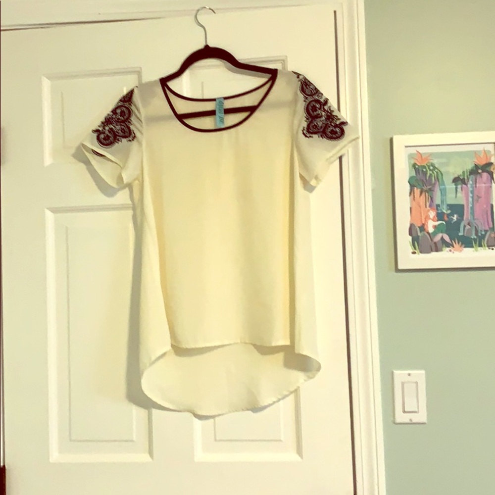 White top with navy embroidery on the sleeves